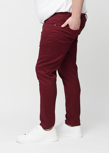 Dunkelrote Jeans im Slim Fit, von der Seite an einem Plus-Size-Model gesehen.