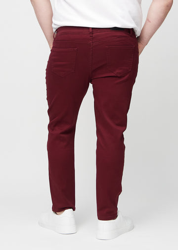 Dunkelrote Jeans im Slim Fit, von hinten an einem Plus-Size-Model gesehen, um die gesamte Jeans zu zeigen.