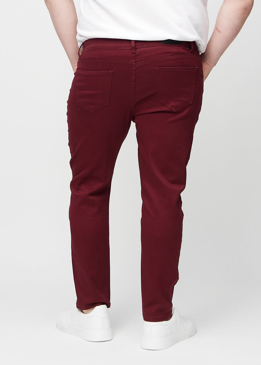 Dunkelrote Jeans im Slim Fit, von hinten an einem Plus-Size-Model gesehen, um die gesamte Jeans zu zeigen.