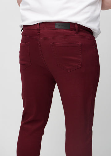 Nahaufnahme von hinten von dunkelrote Jeans im Slim Fit an einem Plus-Size-Model, die Details zeigt.