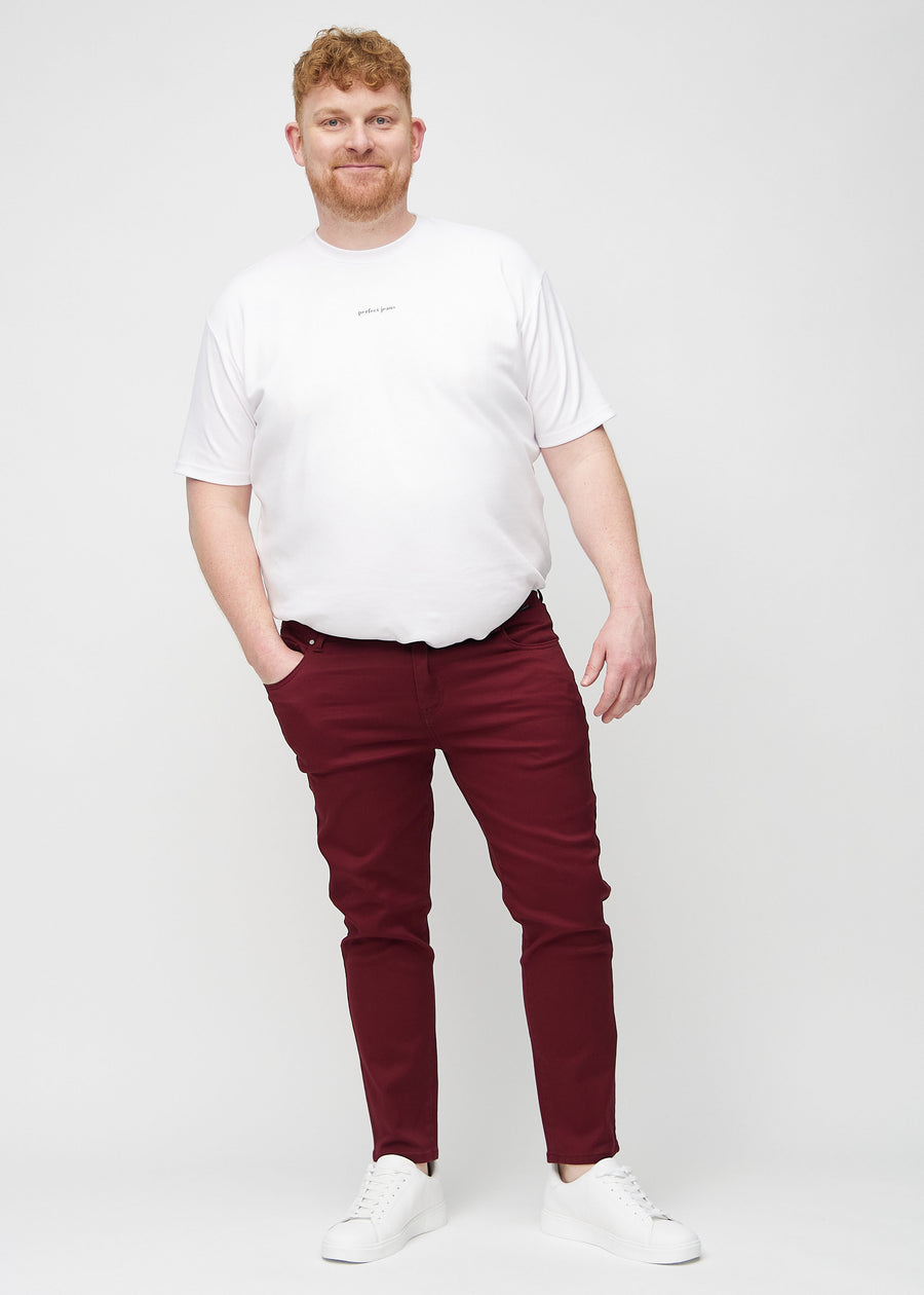 Ganzkörperaufnahme eines Plus-Size-Models in dunkelrote Jeans im Slim Fit.