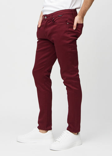 Dunkelrote Jeans im Slim Fit, von der Seite an einem Model gesehen.