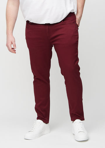 Dunkelrote Jeans im Slim Fit, Modell Santas, die an einem Plus-Size-Model eng an den Beinen anliegen, von vorne gesehen.