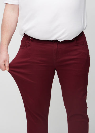 Ein Plus-Size-Model dehnt die Jeans am Oberschenkel, um den Stretch des Materials zu zeigen.