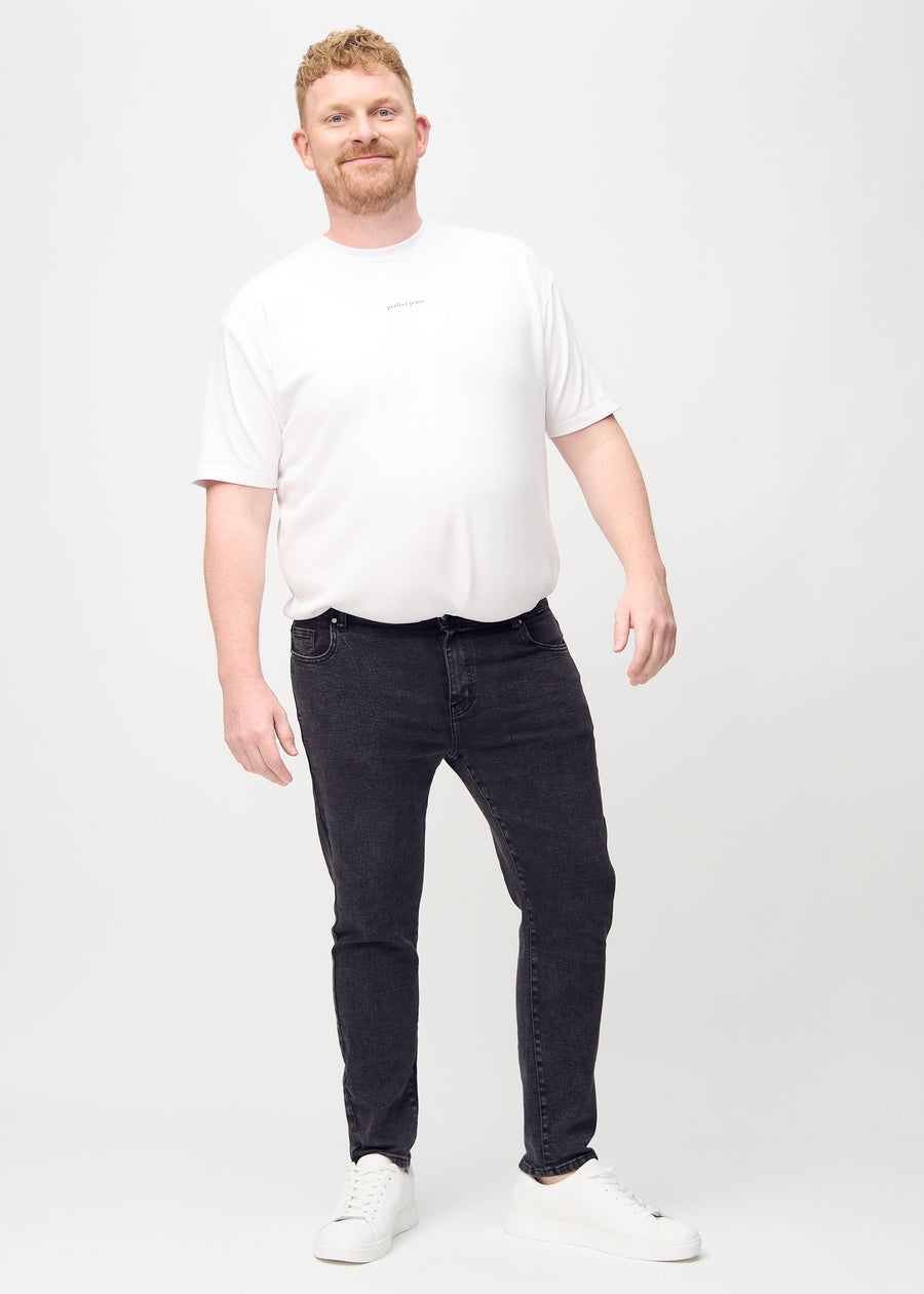 Ganzkörperaufnahme eines Plus-Size-Models in dunkelgraue Denim-Jeans im Slim Fit.