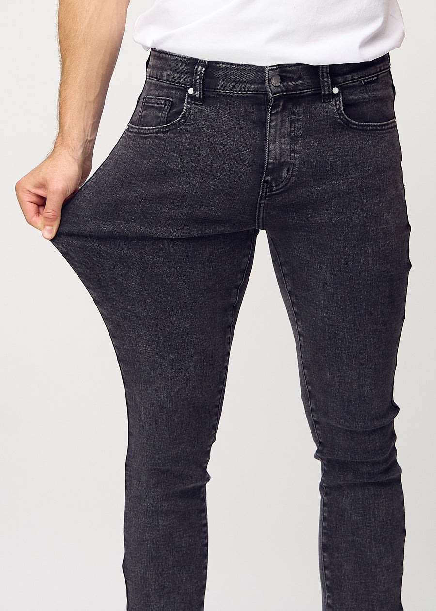 Ein Model dehnt die Jeans am Oberschenkel, um den Stretch des Materials zu zeigen.