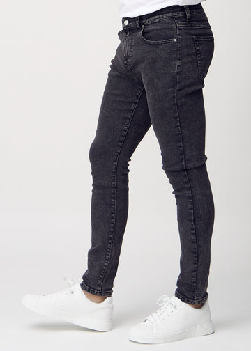 Dunkelgraue Denim-Jeans im Slim Fit, von der Seite an einem Model gesehen.