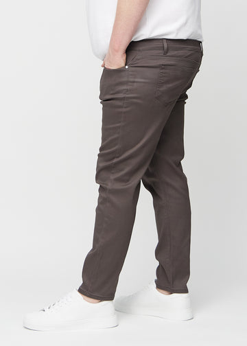 Graubraune Jeans im Slim Fit, von der Seite an einem Plus-Size-Model gesehen.