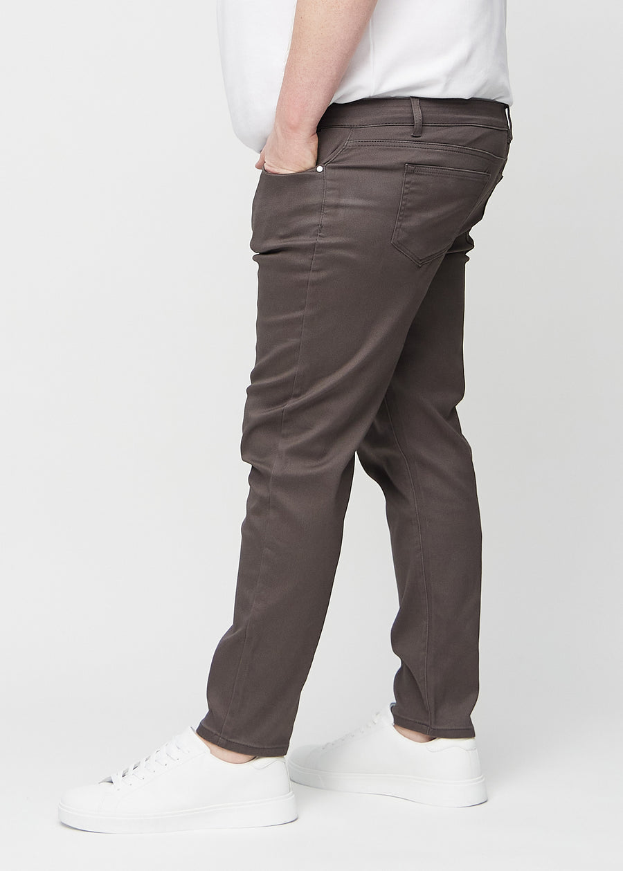 Graubraune Jeans im Slim Fit, von der Seite an einem Plus-Size-Model gesehen.