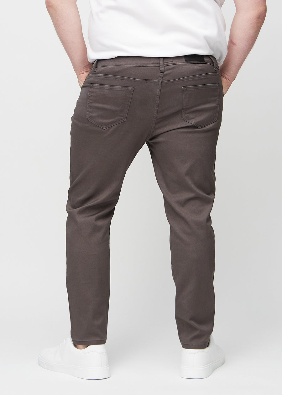 Graubraune Jeans im Slim Fit, von hinten an einem Plus-Size-Model gesehen, um die gesamte Jeans zu zeigen.