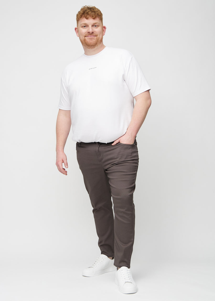 Ganzkörperaufnahme eines Plus-Size-Models in graubraune Jeans im Slim Fit.