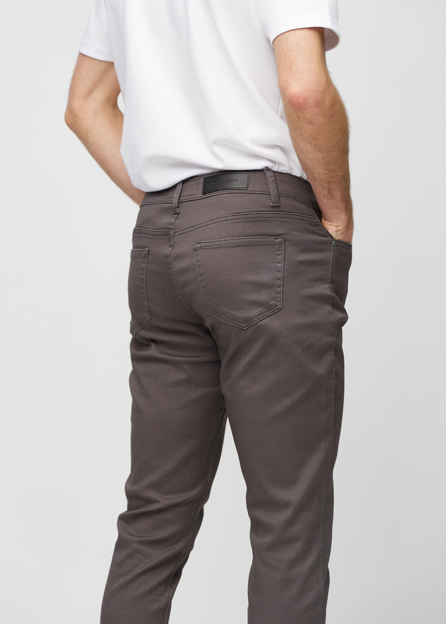 Nahaufnahme von hinten von graubraune Jeans im Slim Fit, die Details zeigt.