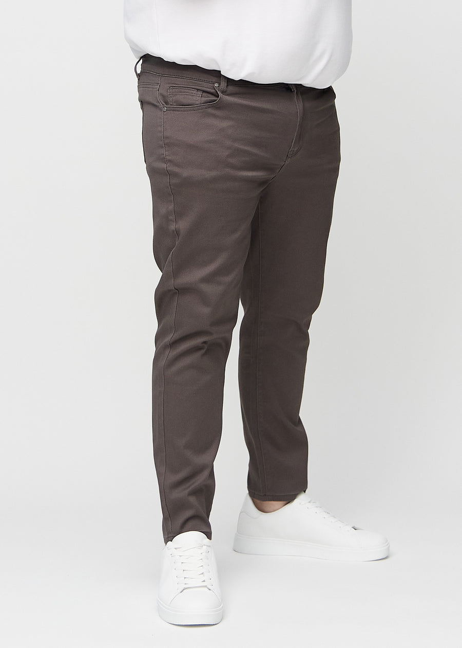Graubraune Jeans im Slim Fit, Modell Thunders, die an einem Plus-Size-Model eng an den Beinen anliegen, von vorne gesehen.