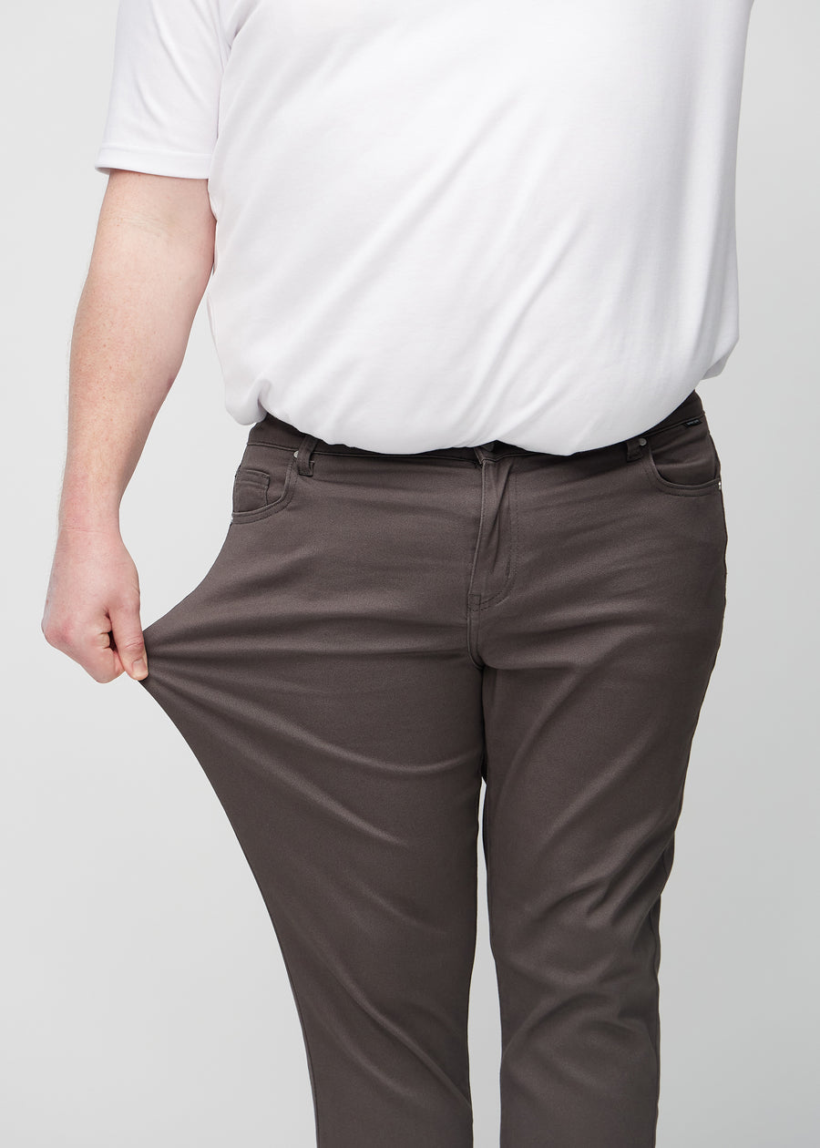 Ein Plus-Size-Model dehnt die Jeans am Oberschenkel, um den Stretch des Materials zu zeigen.