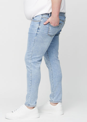 Hellblaue Denim-Jeans im Slim Fit, von der Seite an einem Plus-Size-Model gesehen.