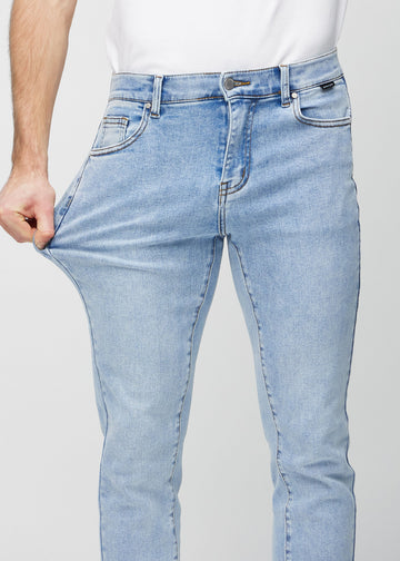 Ein Model dehnt die Jeans am Oberschenkel, um den Stretch des Materials zu zeigen.