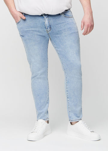 Hellblaue Denim-Jeans im Slim Fit, Modell Waves, die an einem Plus-Size-Model eng an den Beinen anliegen, von vorne gesehen.