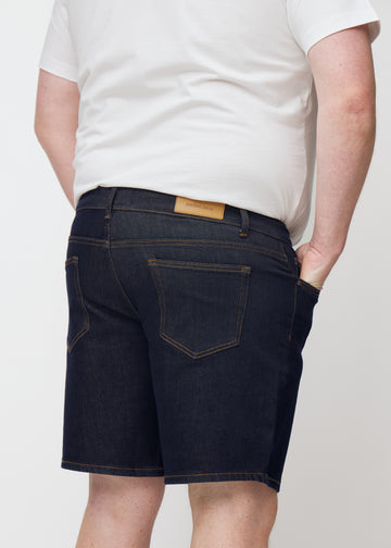 dunkelblaue denim shorts für herren in der farbe midnights von hinten nah auf einem plus-size-model aufgenommen.