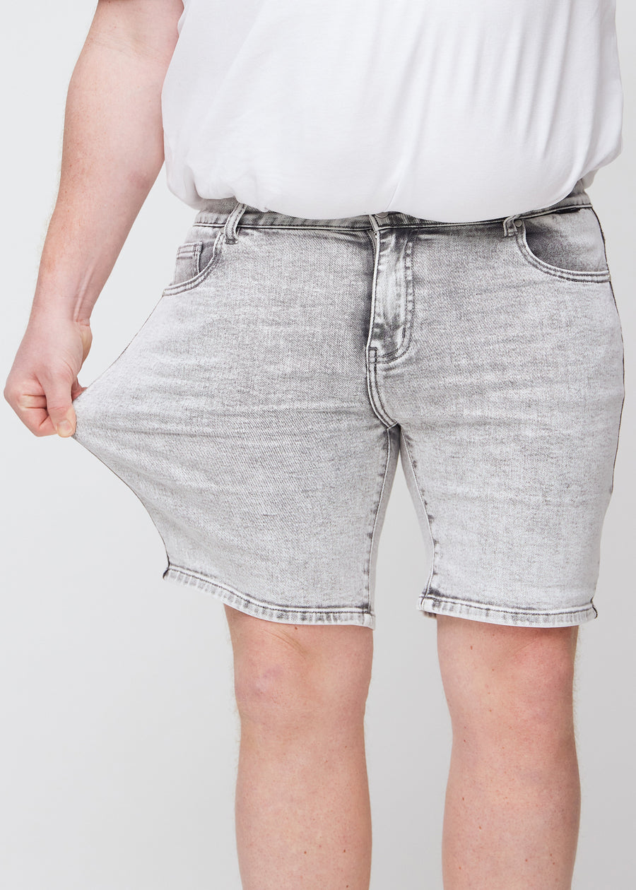 Das Plus-Size-Model zieht die Shorts am Oberschenkel auseinander, um den Stretch zu zeigen.