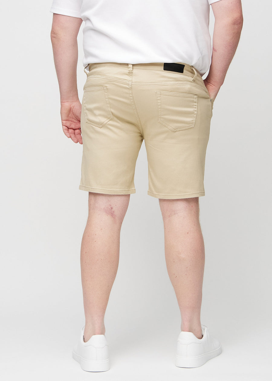 Beige middle-slim Shorts an einem Plus-Size-Model von hinten gesehen, damit man das gesamte Produkt sehen kann.