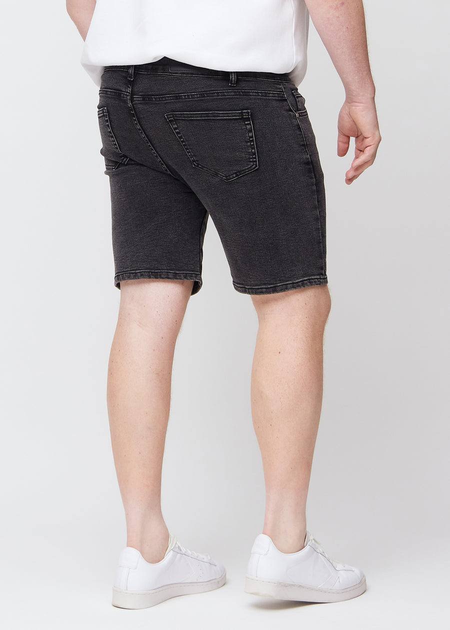 Dunkelgraue Denim middle-slim Shorts von hinten an einem Plus-Size-Model gesehen, damit man das gesamte Produkt sehen kann.