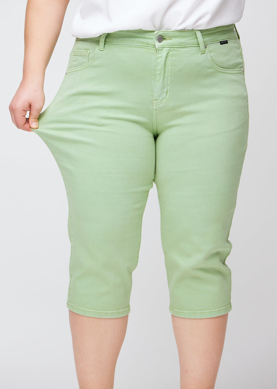 Plus-size model viser stretch ved at trække i caprisene ved låret – fokus på komfort og fleksibilitet.
