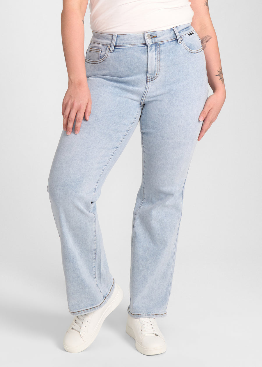 Lyseblå denim bootcut jeans, modelnavn Waves, som sidder tæt om hofter og lår med et let svaj fra knæet og ned, set forfra på en plus-size model.