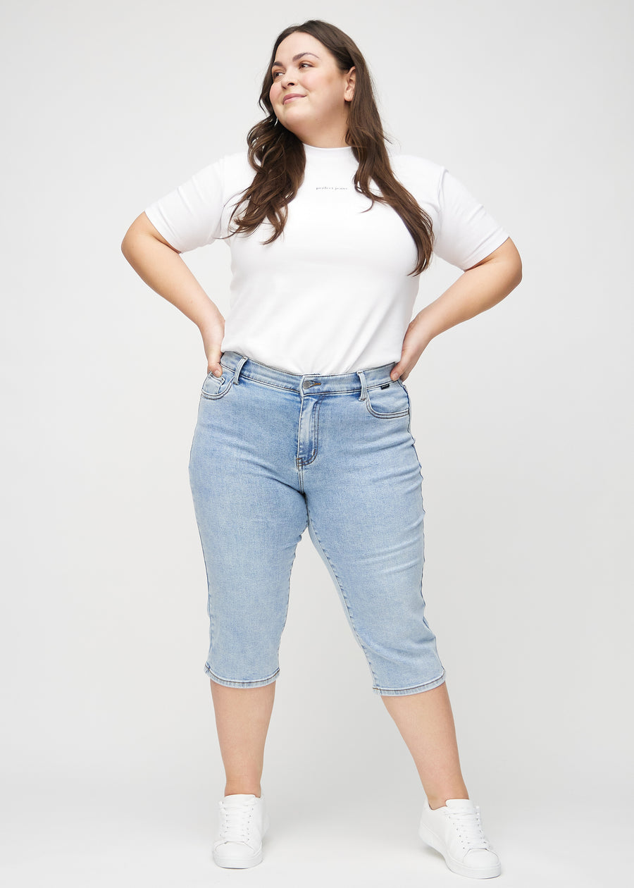 Plus-size model går ind i billedet, strækker i sine capris, viser dem frem ved at dreje rundt, og forlader derefter billedet.