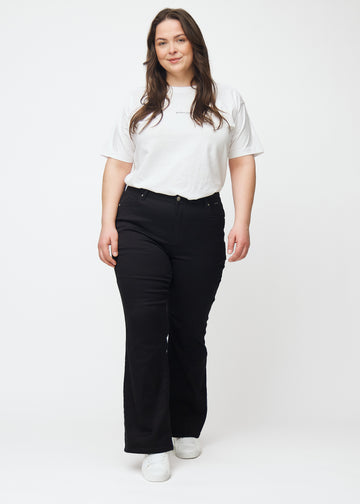 Plus-size model går ind i billedet, strækker i jeansene, viser dem frem ved at dreje rundt og forlader derefter billedet.