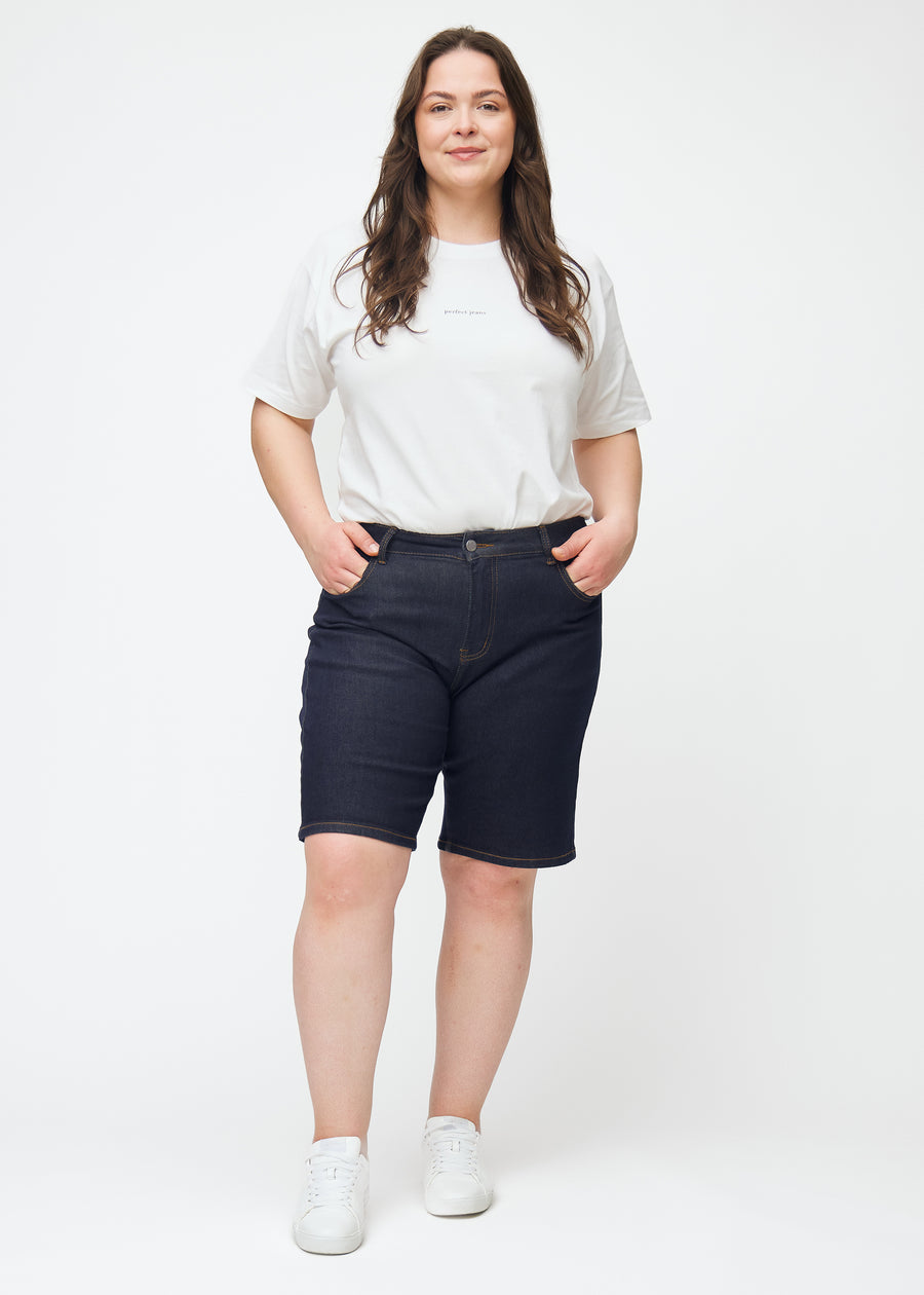 Plus-size model viser dyb mørkeblå denim shorts til kvinder i farven Midnights med regular pasform i bevægelse.