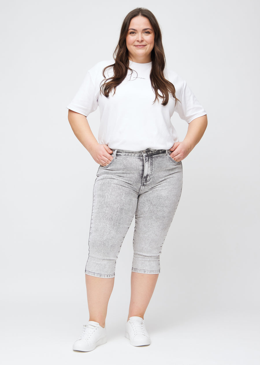 Plus-size model går ind i billedet, strækker i sine capris, viser dem frem ved at dreje rundt, og forlader derefter billedet.